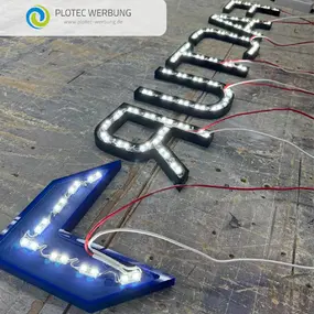 LED-Leuchtbuchstaben einer Werbeanlage auf Werkbank, Kabel sichtbar
