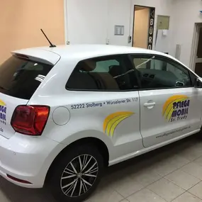 Weißes Pflege-Mobil Auto mit Werbebeschriftung in Werkstatt, Seitenansicht