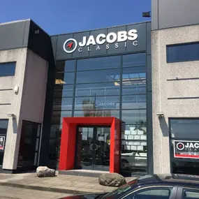 Eingang der Autowerkstatt Jacobs Classic mit Glasfassade und rotem Portal