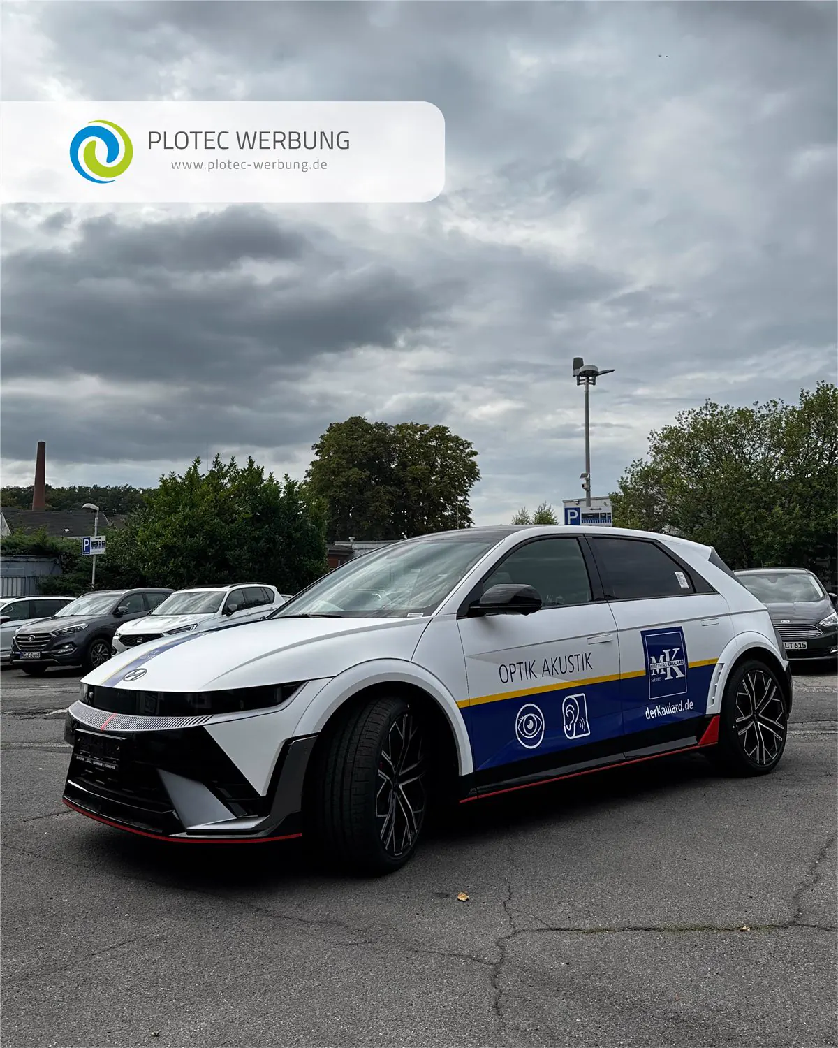 Fahrzeugbeschriftung auf weißem Auto für Optik Akustik auf Parkplatz